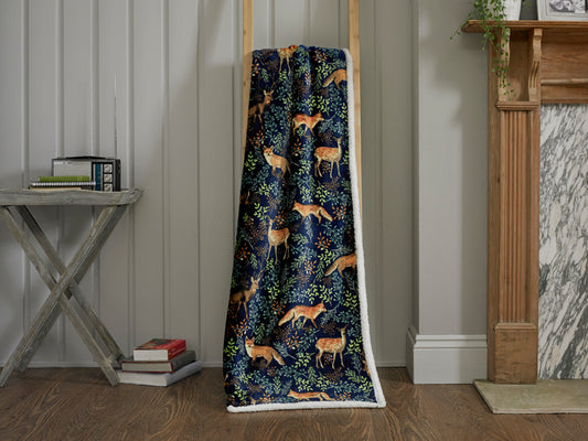 Decorative blanket with fox pattern draped over a wooden frame in a room setting.