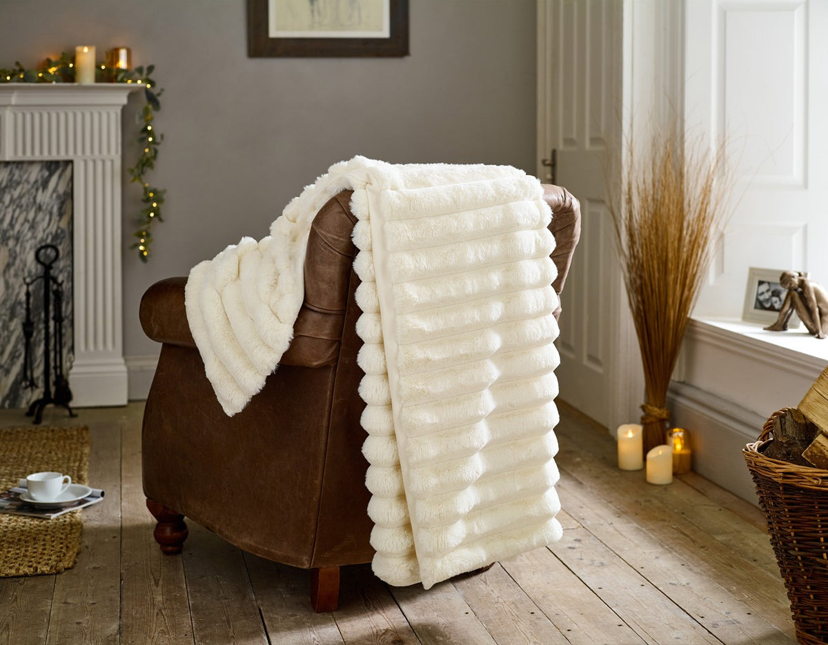 Kenwood Faux Fur Throw in Cream, over a leather armchair
