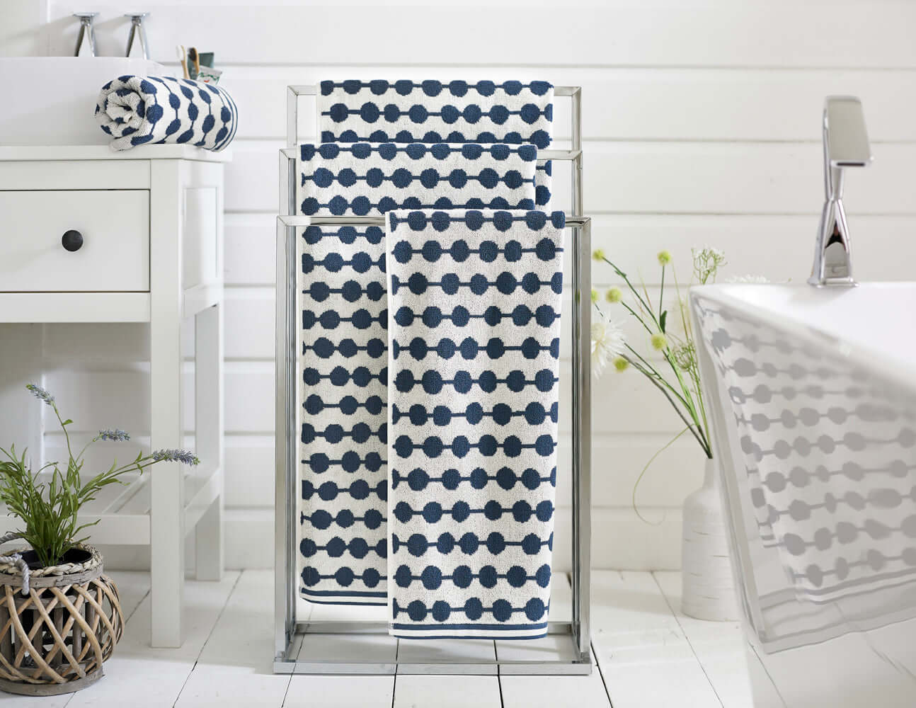 Stylish navy and white Deyongs cotton towels on a rack, perfect for adding luxury and absorbency to any bathroom or spa.