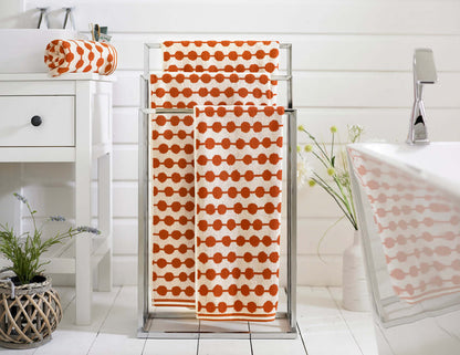 Soft, absorbent cotton towels in bold orange dot pattern, perfect for bathroom or spa, by Deyongs.